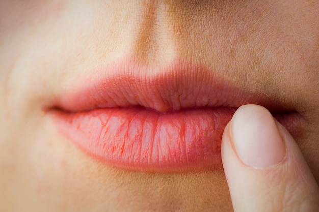 Mujer apuntando a sus labios