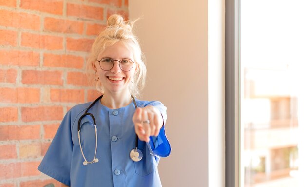 mujer apuntando hacia ti con una sonrisa satisfecha, confiada y amistosa, eligiéndote