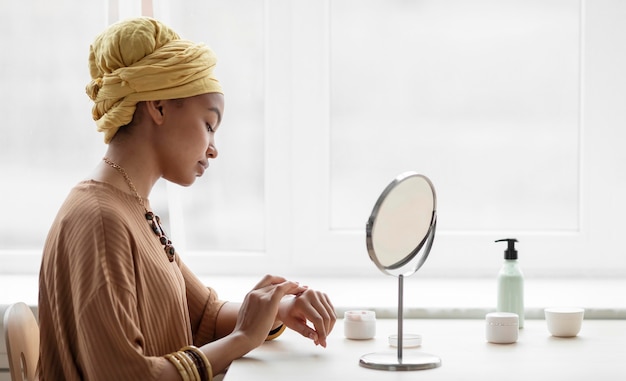 Foto mujer árabe aplicando crema en sus manos. tratamiento de belleza