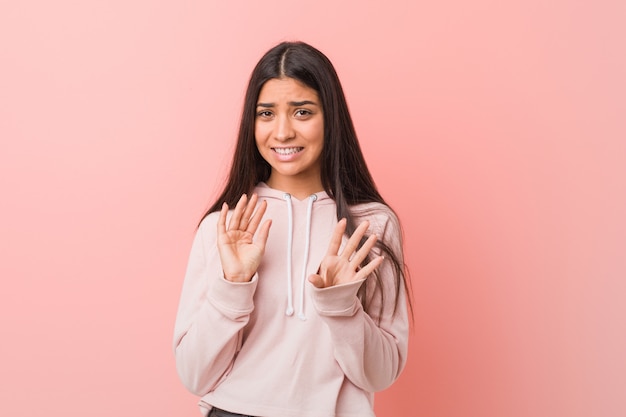 La mujer árabe bonita joven que lleva una mirada casual del deporte que rechaza a alguien que muestra un gesto de repugnancia.