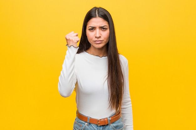 Mujer árabe bonita joven que muestra el puño a la cámara, expresión facial agresiva.