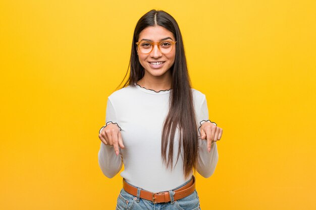 La mujer árabe bonita joven señala con los dedos, sensación positiva.