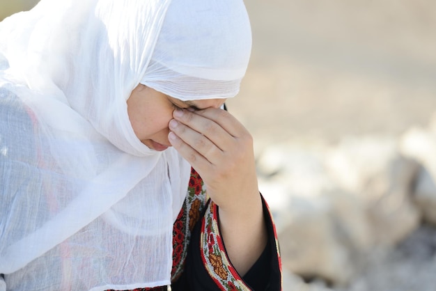 Mujer árabe desesperada sentada sobre una roca y llorando