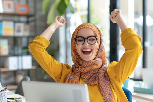 Una mujer árabe exitosa trabaja en una computadora portátil en una oficina brillante que irradia positividad y felicidad