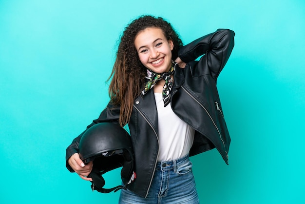 Mujer árabe joven con un casco de motocicleta aislado sobre fondo azul riendo