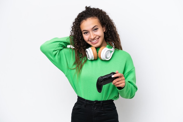 Mujer árabe joven jugando con un controlador de videojuegos aislado sobre fondo blanco riendo