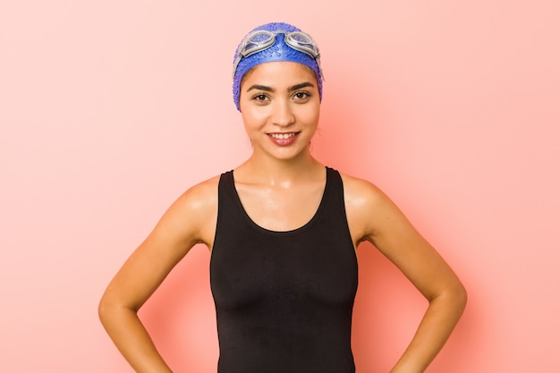 Foto la mujer árabe joven del nadador aisló confiado manteniendo las manos en caderas.