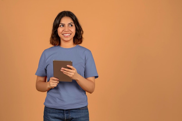 Mujer árabe joven positiva con tableta mirando el espacio de copia