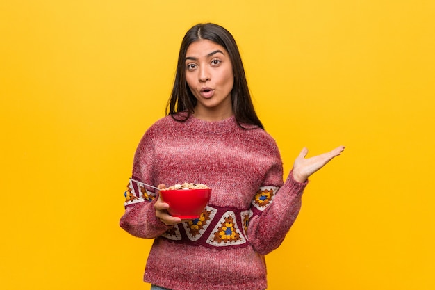 Mujer árabe joven que sostiene un cuenco de cereales impresionó la celebración de copia en la palma.