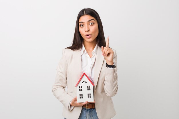 Mujer árabe joven que sostiene un icono de la casa que tiene una gran idea, concepto de creatividad.