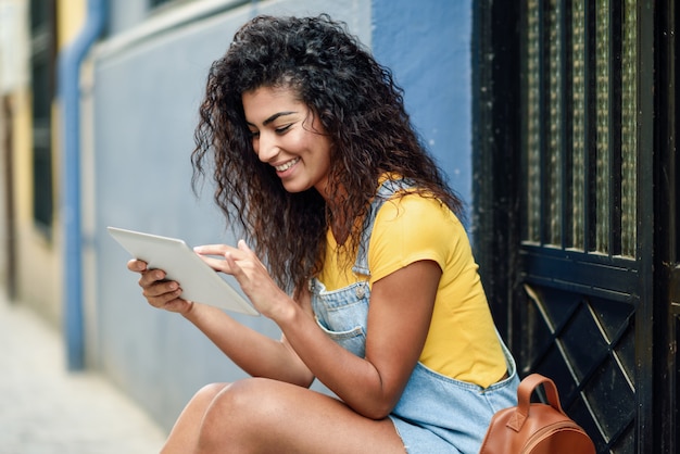 Mujer árabe joven que usa su tableta digital al aire libre