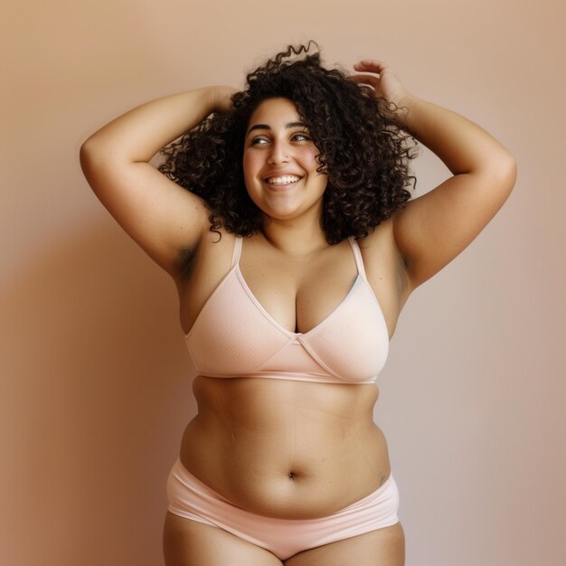 Mujer arabe sonriente abrazando su cuerpo mientras esta de pie en un estudio en ropa interior Imagen Premium generada con IA