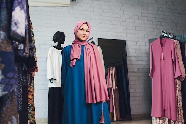 Mujer árabe vestida tradicional musulmana compra un vestido nuevo en una tienda oriental