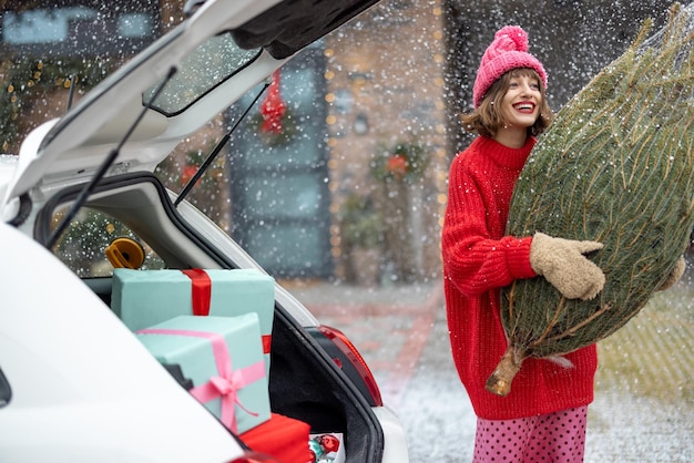 Mujer con árbol de navidad envuelto en el porche de su casa