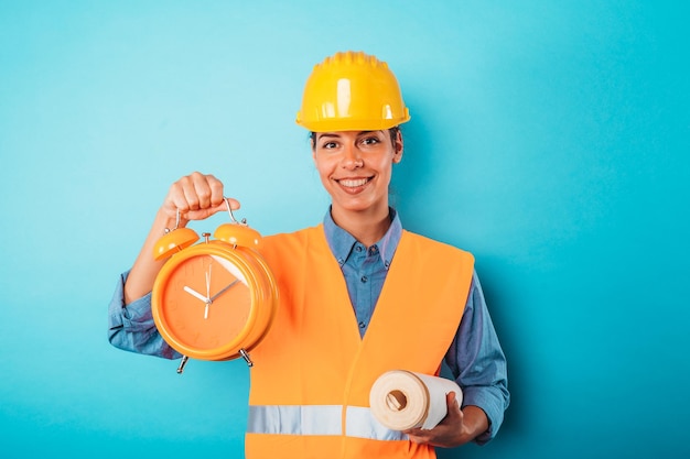 Mujer arquitecta segura con casco y reloj despertador