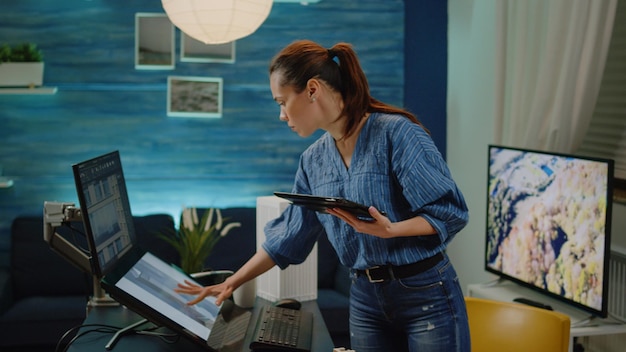 Mujer arquitecta sosteniendo tableta analizando planos y maquetas en la mesa. Planificador de construcción utilizando un dispositivo con pantalla táctil para el modelo de construcción y el plan de desarrollo. Arquitectura digital