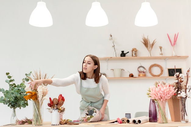 Foto mujer arreglando ramos de flores en su tienda