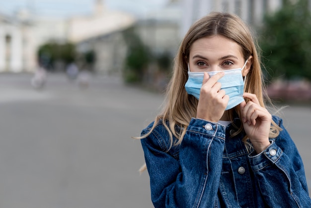 Mujer arreglando su máscara médica para protección