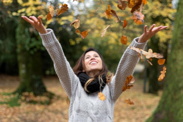 Mujer arrojando hojas durante el otoño