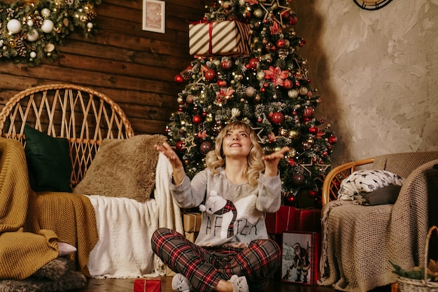 Mujer arrojando un regalo, concepto del año nuevo, interior acogedor de Navidad
