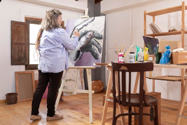 Mujer artista madura pinta con alegría en su taller