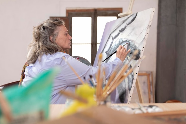 Foto mujer artista madura pintando en su taller