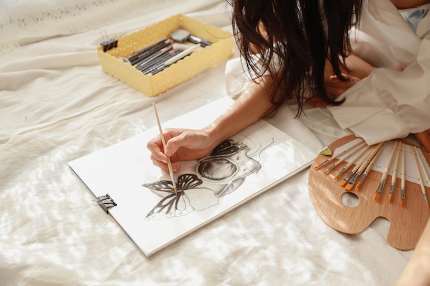 Mujer artista mano en camisa blanca pintura cuadro con lápiz en el salón (concepto de estilo de vida de mujer)