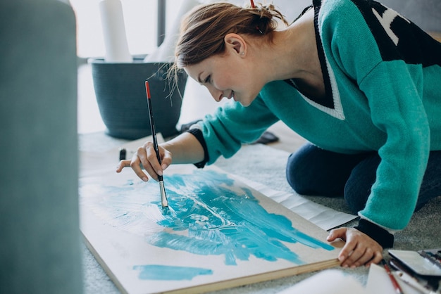 Mujer artista pintando un cuadro en casa