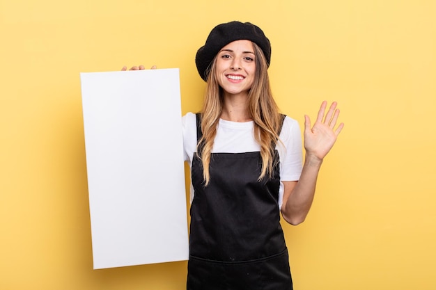 Mujer artista sonriendo alegremente saludando con la mano dándole la bienvenida y saludando el concepto de lienzo vacío