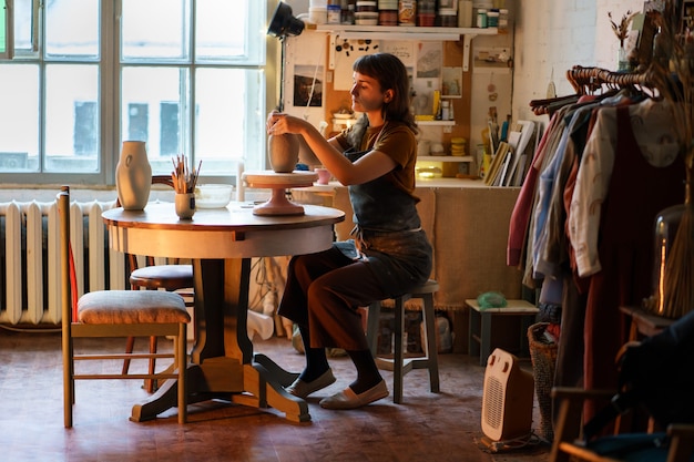 Mujer artística centrada en la producción de cerámica en un pequeño estudio, niña artista dedica tiempo a trabajar con arcilla