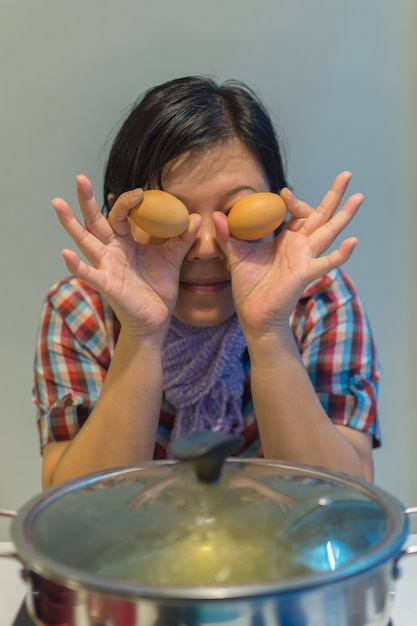 Foto mujer de asia cocinando poner un huevo de carne en una olla caliente