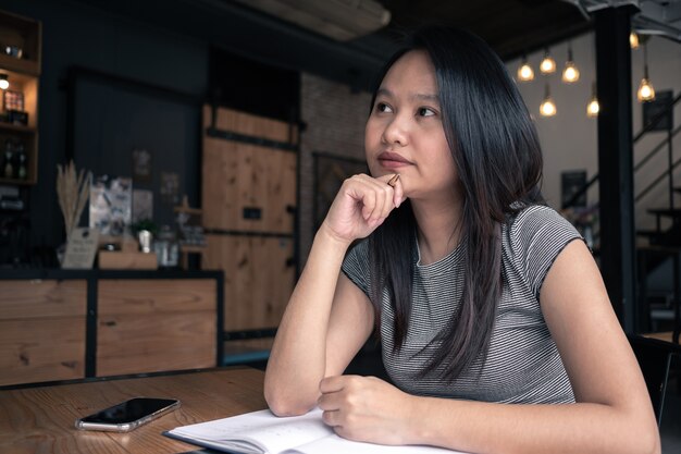 Foto mujer de asia pensando en la cafetería. concepto de idea