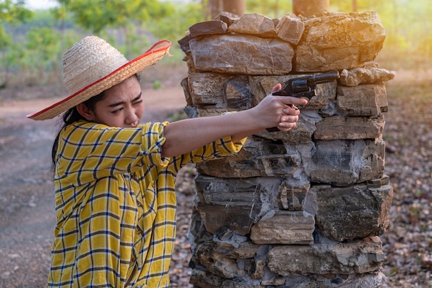 Mujer de Asia con sombrero en el disparo de una vieja pistola revólver en la faAsia