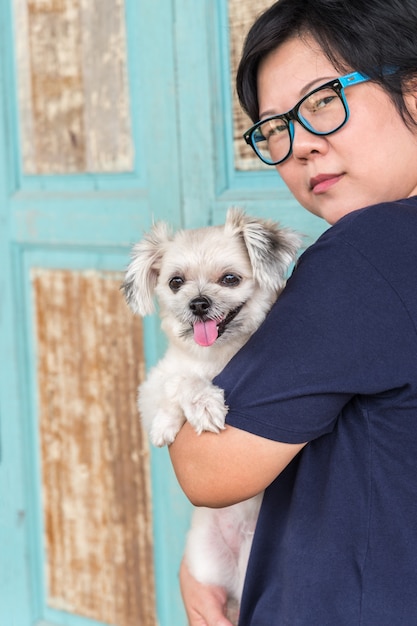 Mujer asiática abrazando perro tan lindo con pared de madera