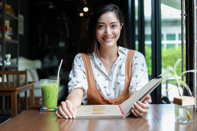 Mujer asiática abre menú para pedir en el café