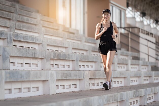 Una mujer asiática adulta sana corriendo por las escaleras de hormigón del estadio de la ciudad para fortalecer el cuerpo