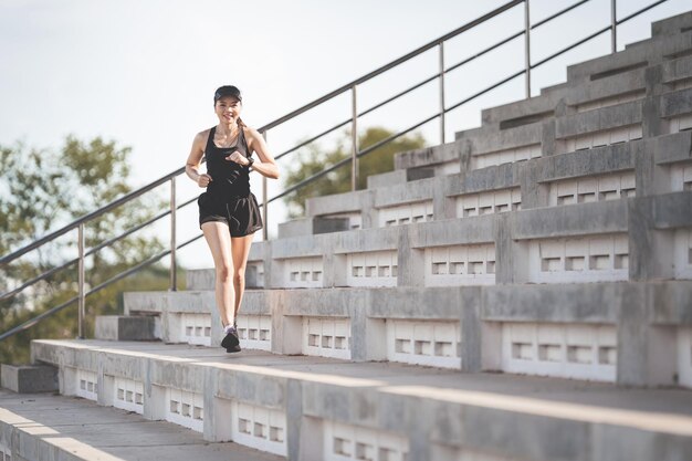 Una mujer asiática adulta sana corriendo por las escaleras de hormigón del estadio de la ciudad para fortalecer el cuerpo
