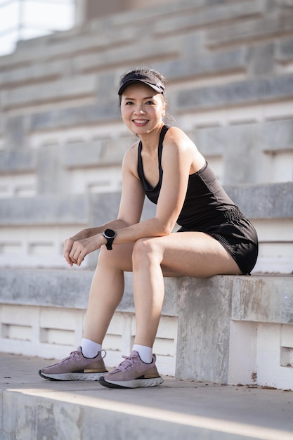 Una mujer asiática adulta sana corriendo por las escaleras de hormigón del estadio de la ciudad para fortalecer el cuerpo