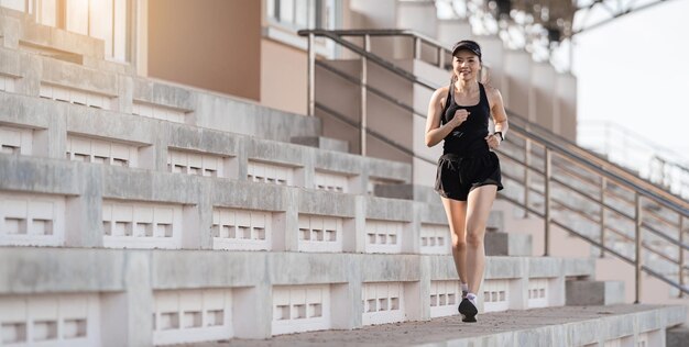 Una mujer asiática adulta sana corriendo por las escaleras de hormigón del estadio de la ciudad para fortalecer el cuerpo