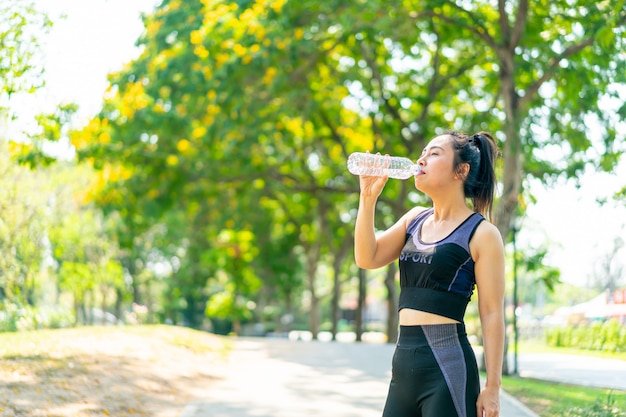 Mujer asiática agua potable en ropa deportiva