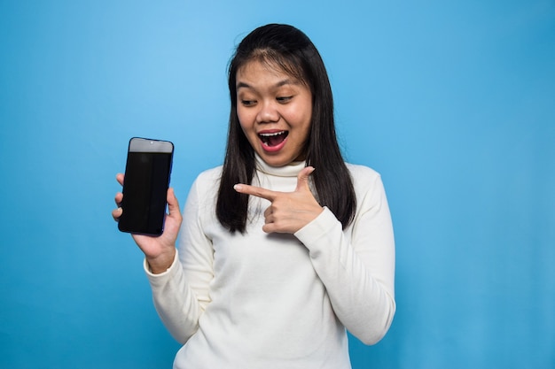 Mujer asiática aislada en azul mostrando buenas aplicaciones de teléfono móvil de pantalla en blanco aplicaciones recomendadas