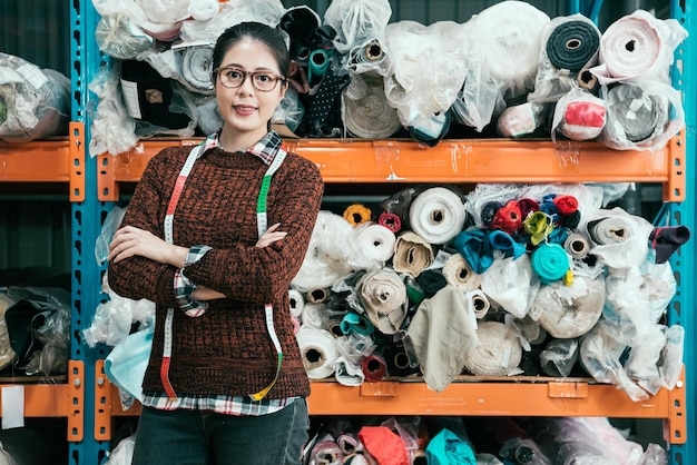 Una mujer asiática se para en el almacén y cruzó las manos y toma una foto con una cómoda sonrisa frente a la cámara.