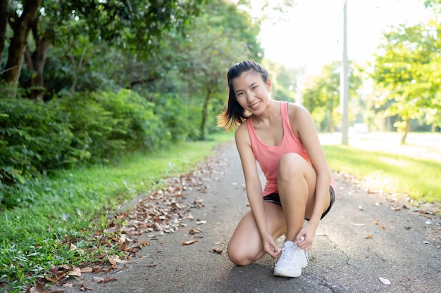 Mujer asiática apretando las correas de los zapatos antes de correr