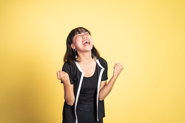 Mujer asiática apretando las manos mientras celebra el éxito