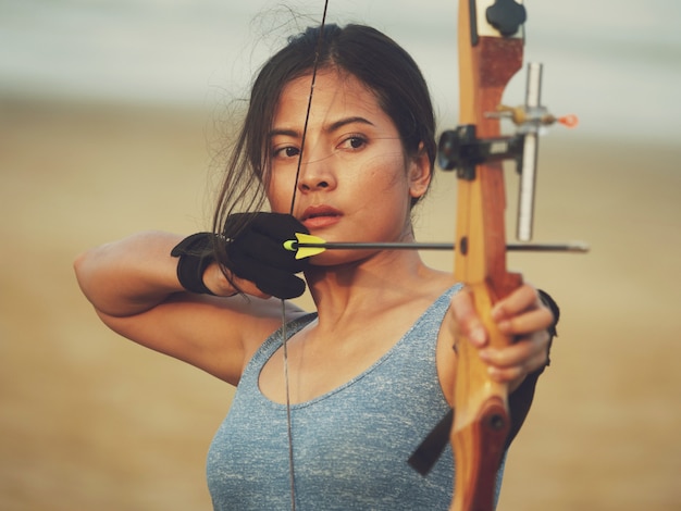Mujer asiática con arco tiro con arco