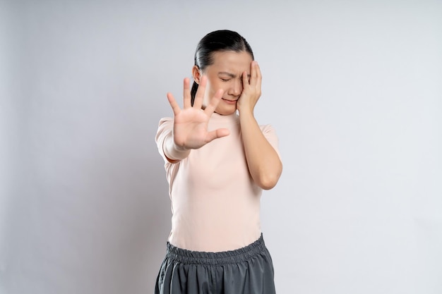 Mujer asiática asustada y cubriéndose la cara con las manos