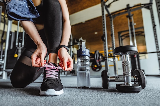 Mujer asiática atarse los cordones de los zapatos Fitness deportivo femenino preparándose para hacer ejercicio en el gimnasio