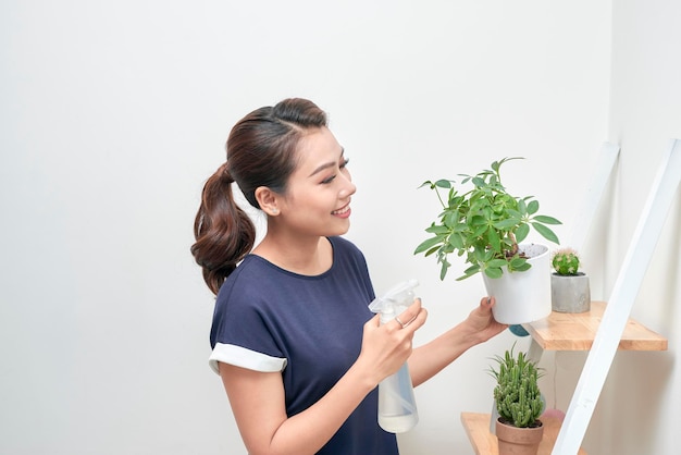 Mujer asiática atractiva joven que da agua a una planta