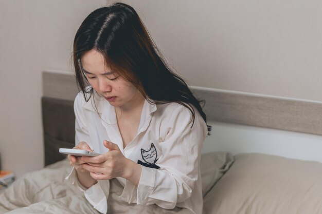 Mujer asiática atractiva joven para ver un teléfono inteligente, mujer sonriente joven que usa el teléfono móvil