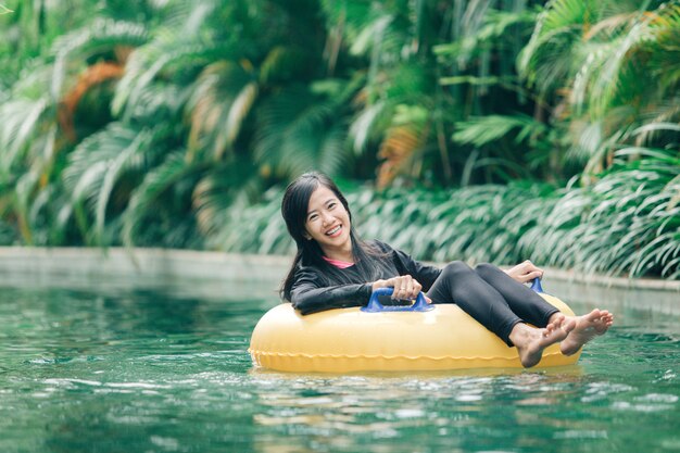 Mujer asiática atractiva que se relaja en la piscina del río